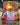 K.B.Kiwi girl kiwi character plush toy inside the box with a blurred outdoor background
