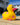 Yellow rubber kiwi bath toy with pink flowers on a concrete surface.