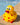 Yellow rubber kiwi bath toy with red hearts on a stone surface near a pool.
