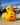 Yellow rubber kiwi bath toy with red hearts on a stone wall with a blue background